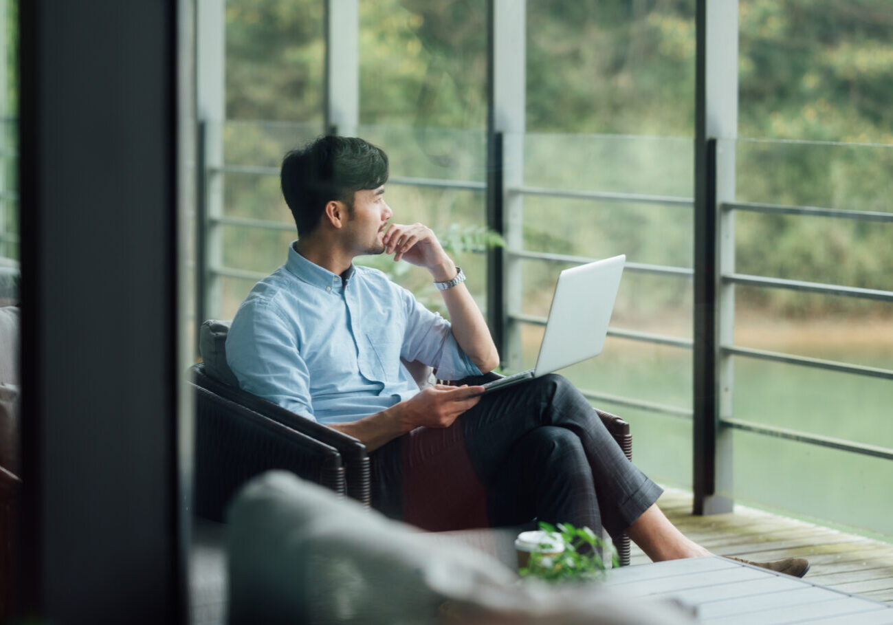 Asian businessman using laptop at office window